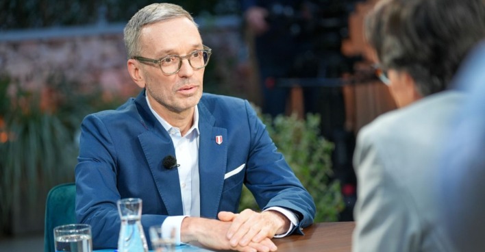 Herbert Kickl sitzt im ORF-Sommergespräch an einem Tisch, trägt Brille und blauen Anzug, spricht mit Moderator Klaus Webhofer.