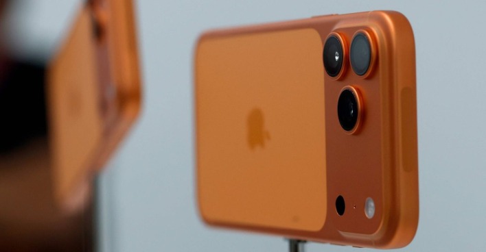 Nahaufnahme eines orangefarbenen iPhone 17 Pro mit drei Kameralinsen auf der Rückseite.