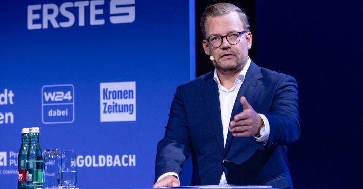 Jürgen Hofer im blauen Anzug vor einem blauen Hintergrund