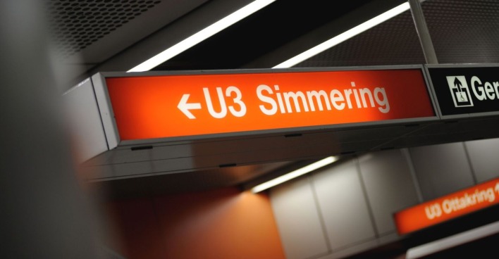 Leuchtendes Hinweisschild in einer Wiener U-Bahn-Station mit der Aufschrift „U3 Simmering“ und einem Richtungspfeil nach links. Daneben ist ein Piktogramm für einen barrierefreien Lift sichtbar.