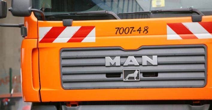 Orangefarbener Müllwagen der Stadt Wien, Nahaufnahme der Frontpartie mit MAN-Logo.