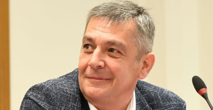 Porträt von Wolfgang Seidl, FPÖ-Politiker aus Wien, lächelnd vor einem Mikrofon.