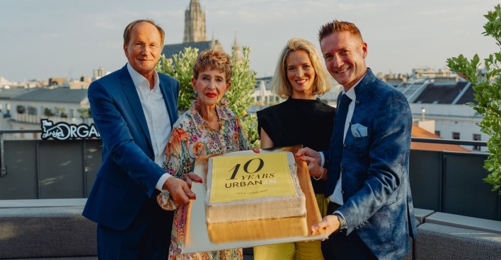 Quartett mit Jubiläumstorte auf einer Dachterrasse mit Blick auf den Stephansdom