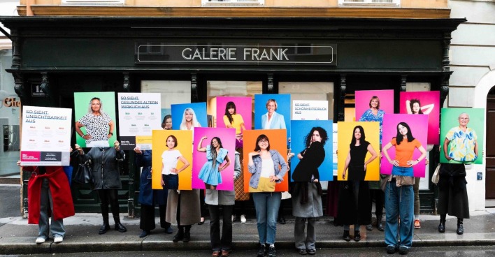 Gruppenbild vor Galerie mit Frauen, die große Porträts von sich hochhalten