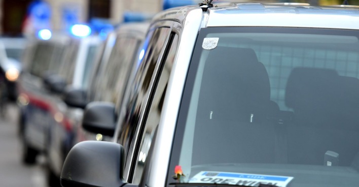 Reihe österreichischer Polizeiautos mit eingeschaltetem Blaulicht in einer Grazer Straße.