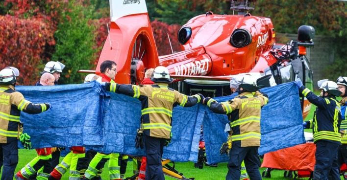 Feuerwehrleute und Sanitäter in Herdecke transportieren die schwerverletzte Iris Stalzer unter Sichtschutz zu einem Rettungshubschrauber nach einem Gewaltverbrechen.
