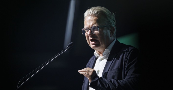 Christopher Drexler spricht gestikulierend in ein Mikrofon bei einer Veranstaltung.