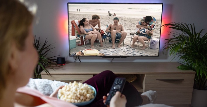 Eine Frau schaut Fernsehen und isst Popcorn