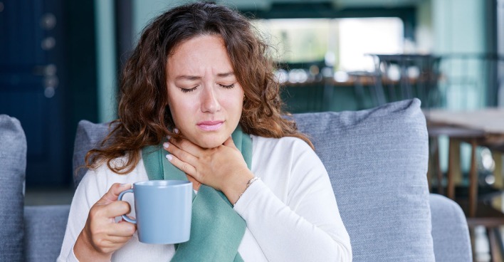 Frau greift sich an Hals | Credit: iStock.com/eternalcreative