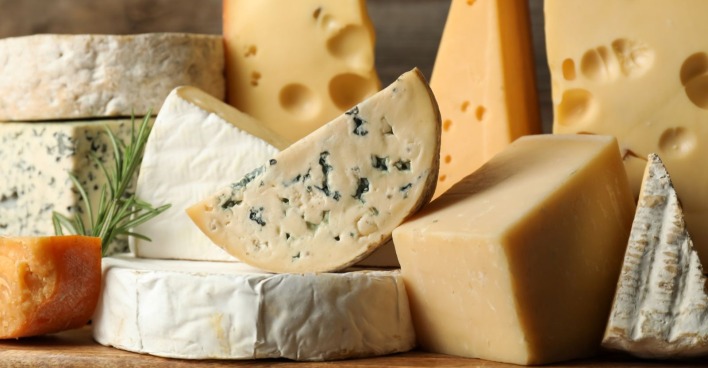 Mehrere Sorten Käse auf einem Holztisch, symbolisch für den aktuellen Metro-Rückruf von Raclette-Käse wegen Listerienverdachts.