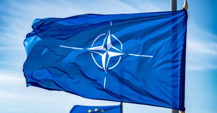NATO-Flagge schwenkt an einem Fahnenmast im Hintergrund weht eine Flagge der Europäischen Union