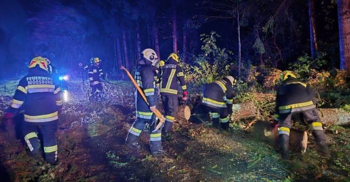 Feuerwehrleute der FF Moosburg räumen in der Nacht nach einem Sturm umgestürzte Bäume von einer Straße in Kärnten.