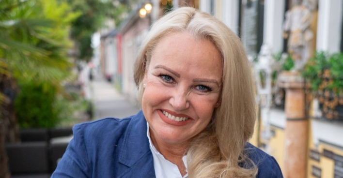 Porträt von Verena Scheitz, die lächelnd in die Kamera blickt – die Moderatorin startet nach ihrem ORF-Aus mit Kabarett neu durch.