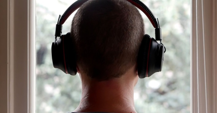 Rückansicht einer Person mit schwarzen Over-Ear-Kopfhörern vor einem Fenster, stellvertretend für den VKI-Schadstofftest bei Kopfhörern.