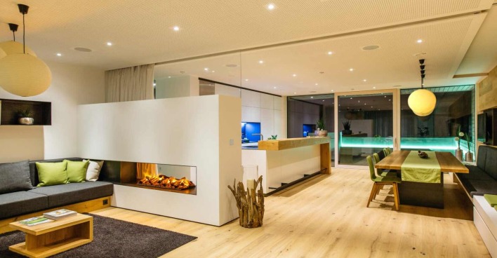 Modernes Wohn- und Esszimmer in einem Loxone Smart Home mit offenem Kamin, stilvoller Beleuchtung, Holzdesign und automatisierter Haussteuerung.