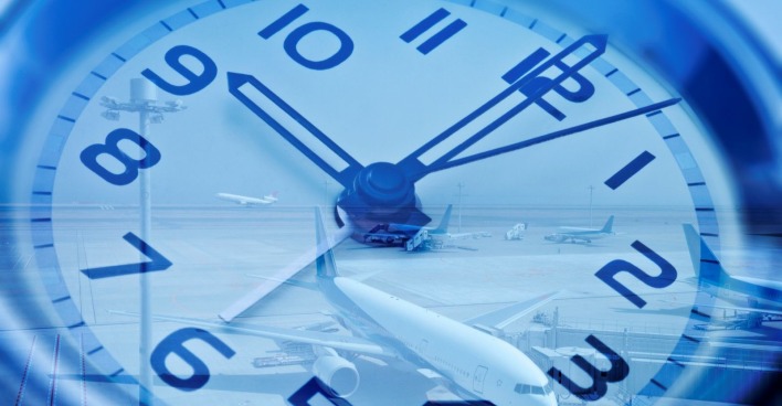 Symbolfoto: Große Uhr mit Blick auf Flugzeuge am Flughafen, Sinnbild für Jetlag und Zeitverschiebung.