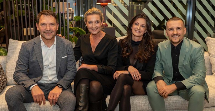 Vier Menschen, die auf einer Couch sitzen und in die Kamera lachen