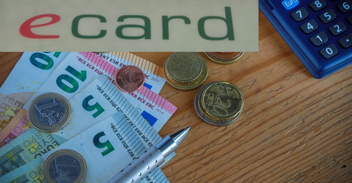 Tisch mit Geldscheinen und einem Taschenrechner über dem das E-Card-Logo steht