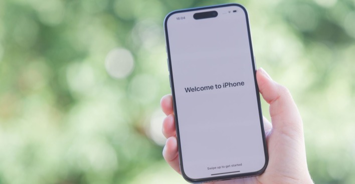 Ein Apple iPhone 15 Pro Smartphone in der Vorderansicht mit der standardisieren Begrüßungsnachricht in der Farbvariante Space Black.