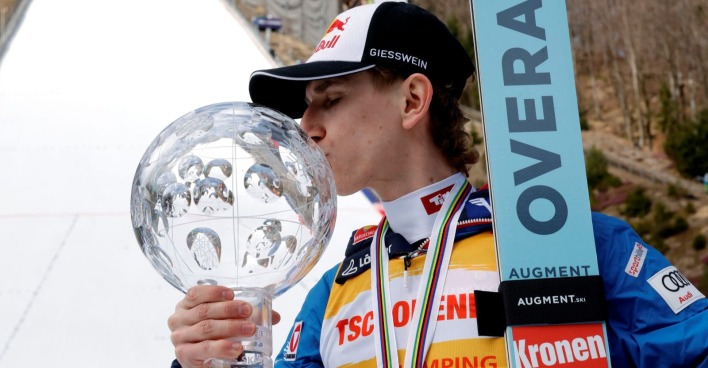 Daniel Tschofenig im Trikot des Gesamtweltcupführenden in Planica mit der Trophäe für den Gesamtweltcupsieg in Skispringen