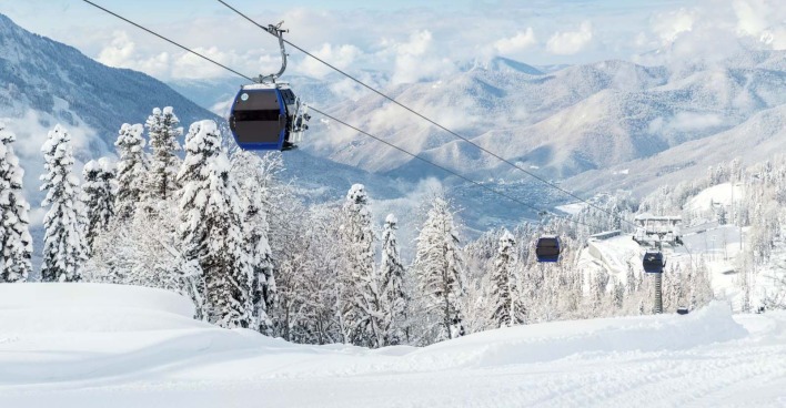 Seilbahn mit einer verschneiten Winterlandschaft im Hintergrund