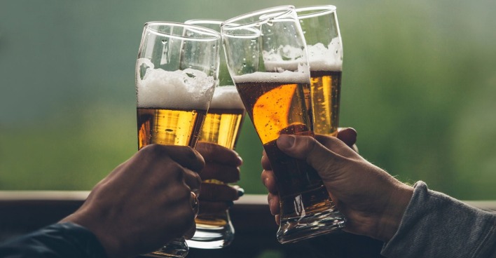 Bier mit schaumleichten großen Jungs in den Händen von Freunden, die einen Toast aus der Nähe anstoßen