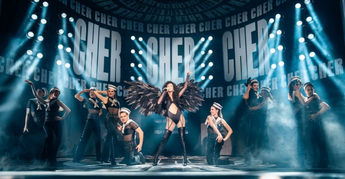 Cher-Darstellerin mit männlichen und weiblichen Tänzern auf der Showbühne