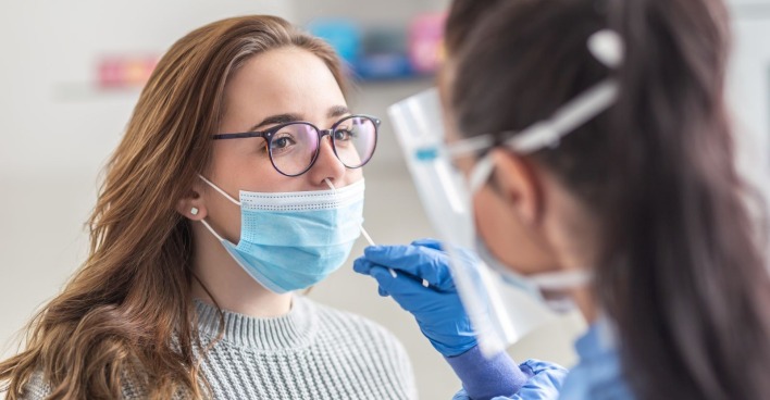 Ärztin untersucht eine Patientin mit einer Maske - die Influenza plagt Österreich und sorgt für eine frühe Grippewelle.