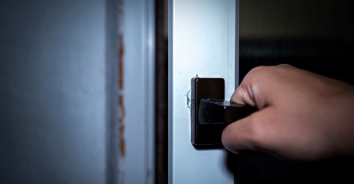Männerhand öffnet die Tür eines Fensters in der Dunkelheit