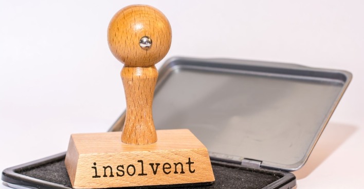 Stempel auf einem Stempelkissen, auf dem Stempel steht das Wort Insolvenz geschrieben
