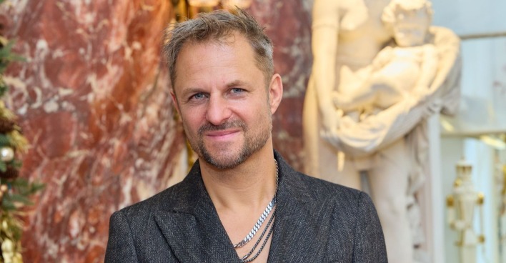 Philipp Hochmair lächelt vor Marmorwand