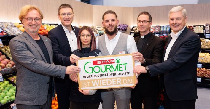 Sechs Personen halten in der Spar-Filiale ein Spar-Gourmet-Schild