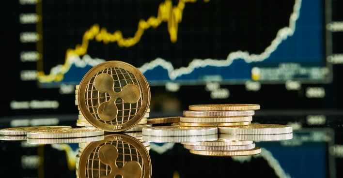 XRP-Kryptowährung auf einer reflektierenden Oberfläche vor einem Markttrenddiagramm