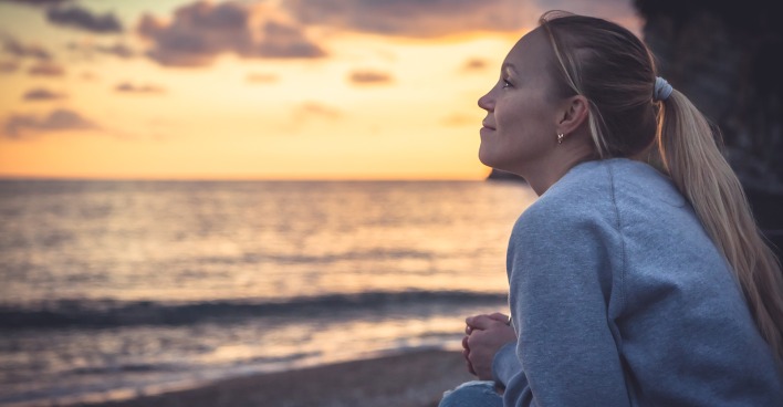 Frau am Strand bei Sonnenuntergang | Credit: iStock.com/splendens