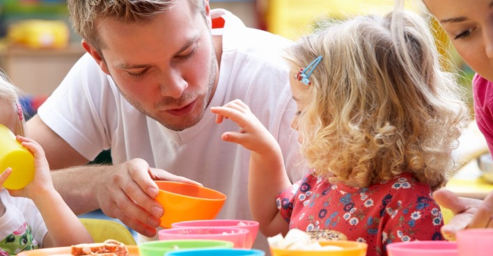 Kindergärtner spricht mit Kind am Tisch
