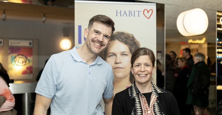 Mann und Frau im Stadtkino vor einem Aufsteller des Hauses der Barmherzigkeit