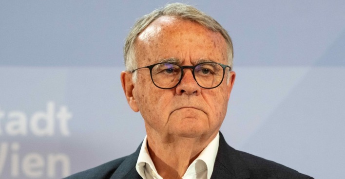 Hans Niessl steht vor einem blauen Hintergrund, trägt Brille und dunkles Sakko – der ehemalige Landeshauptmann des Burgenlandes erwägt eine Kandidatur für die Bundespräsidentenwahl 2028.