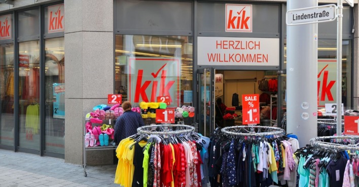 Eingang einer KiK-Filiale mit Kleiderständern und SALE-Schildern vor dem Geschäft.