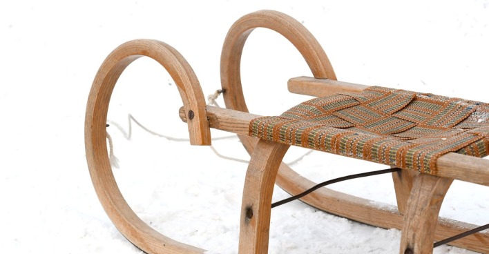 Eine Rodel aus Holz steht im Schnee