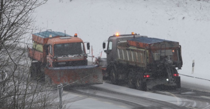 Zwei Schneepflüge räumen eine schneebedeckte Straße in Kärnten während anhaltendem Schneefall.