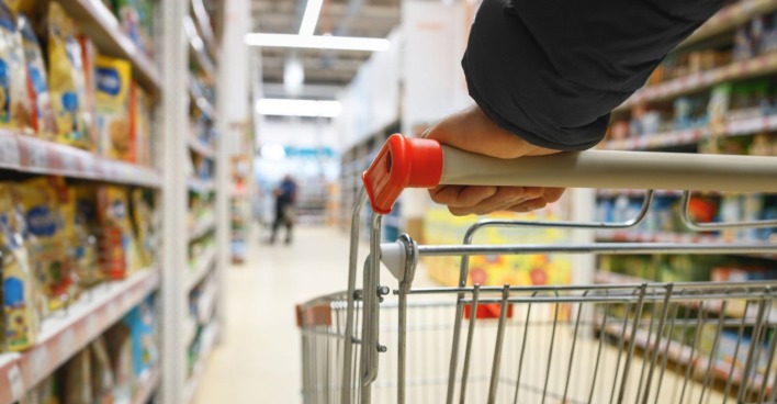 Einkaufswagen in einem Supermarktgang, Symbolbild für neue Kennzeichnungspflicht bei Shrinkflation in Österreich.