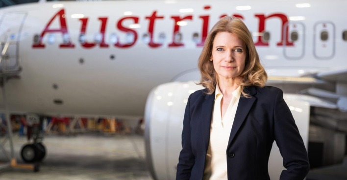 Frau im dunklen Blazer vor einem Flugzeug