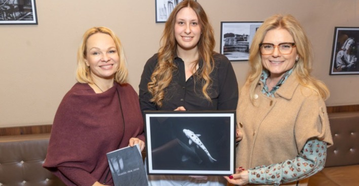 Drei Frauen mit einem Foto der Ausstellung im Café Hummel