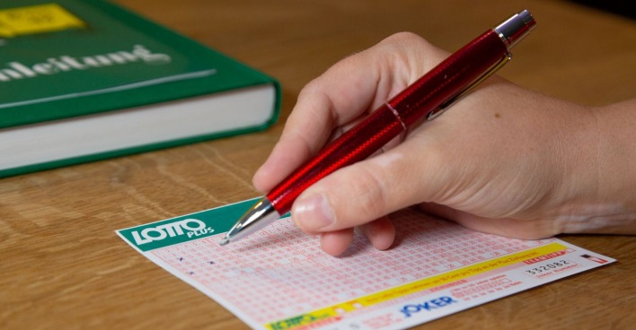 Lotto Ziehung heute: Hand die einen Lottoschein in einer Annahmestelle ausfüllt.