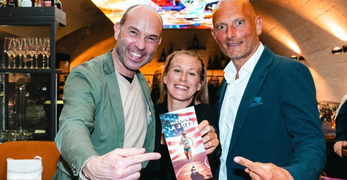 Trio hält Broschüre der Marathon-Rekordhalterin in die Kamera