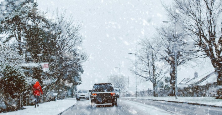 Schnee in Österreich: Winterliches Wetter mit starkem Schneefall auf einer Straße, Autos fahren durch verschneite Landschaft