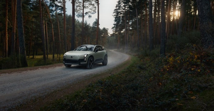 Der Volvo EX60 fährt auf einer Straße im Wald.