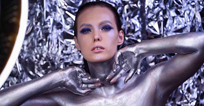 Frau mit silbernem Bodypainting und futuristischem Make-up vor glänzendem Hintergrund – Symbol für moderne Hightech-Beauty