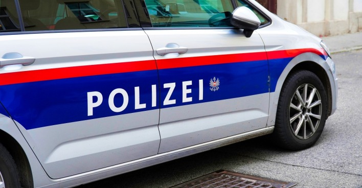 Ein Polizeiauto in Österreich Wien ist in einer ruhigen Straße in einer europäischen Stadt in der Nähe eines Abflusses abgestellt.