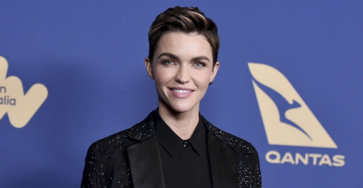 Ruby Rose lächelnd vor einer blauen Wand